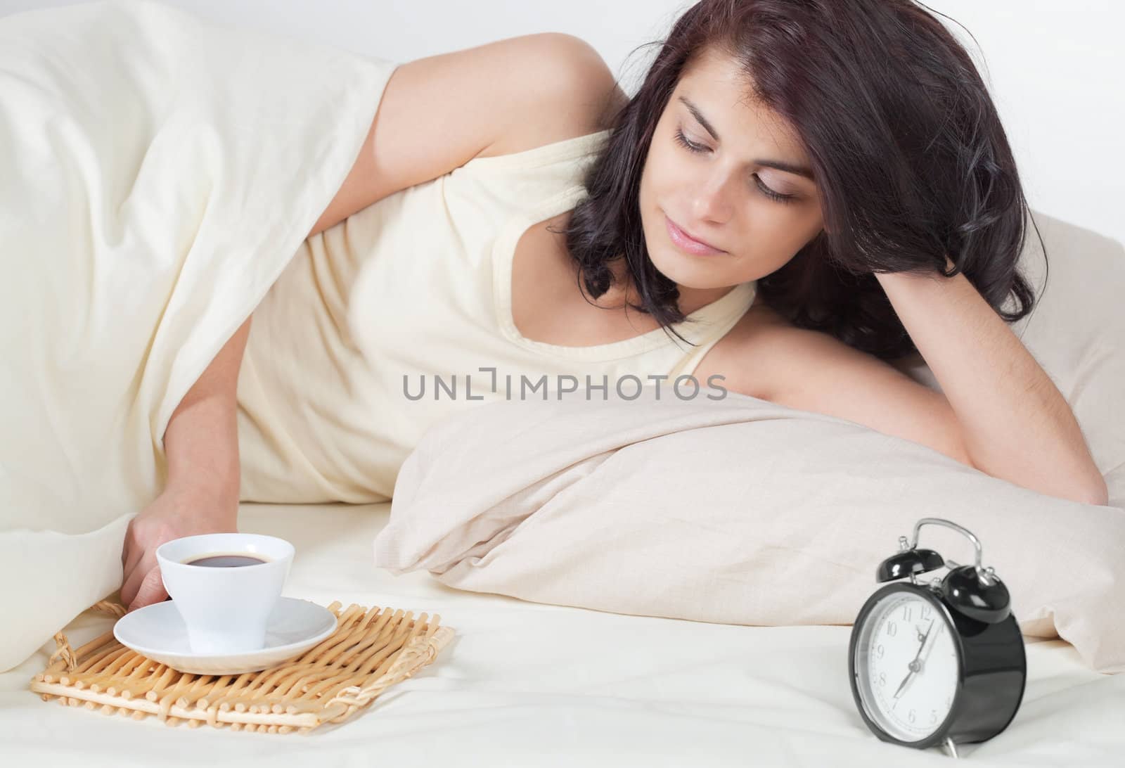 Young woman in bed holding a cup of coffee after she waken up