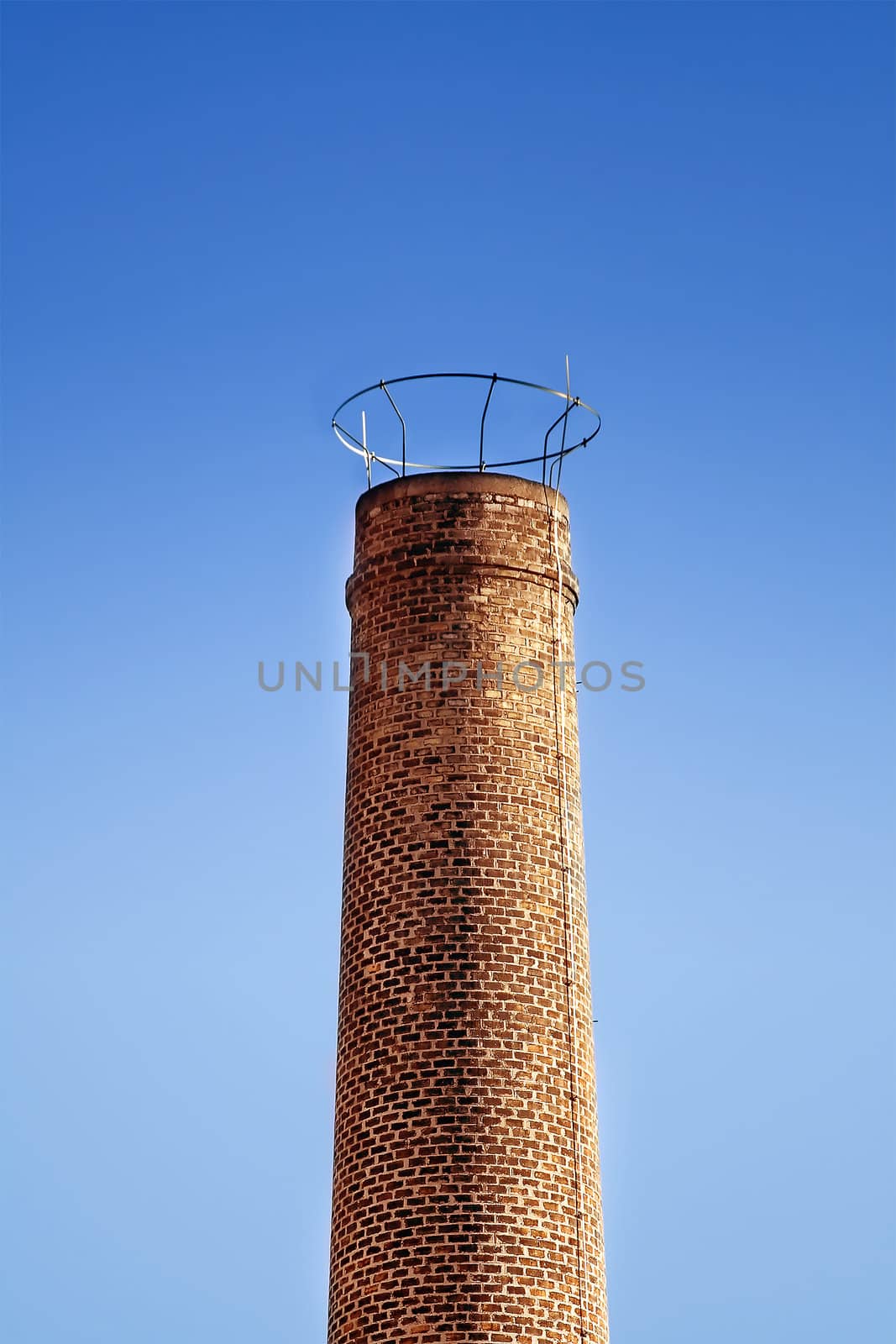 Brick industrial chimney and clear blue sky as background