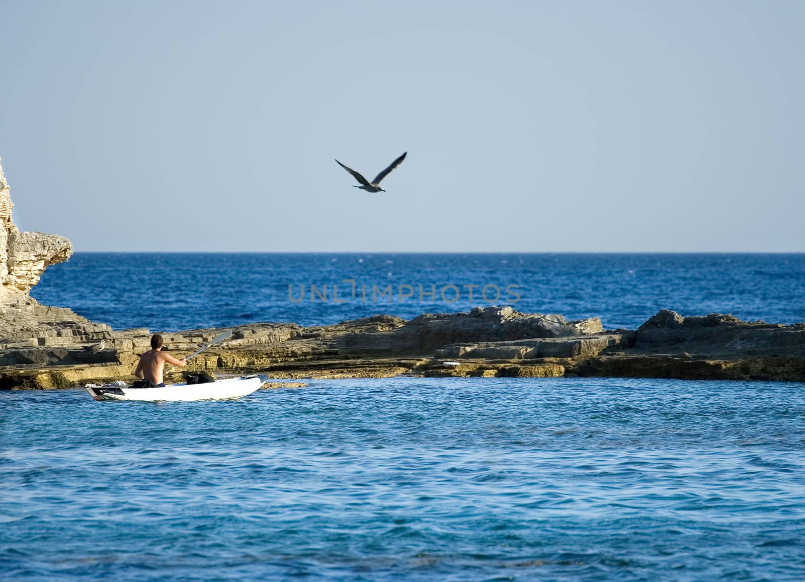 A man kayaking near the rocky beach