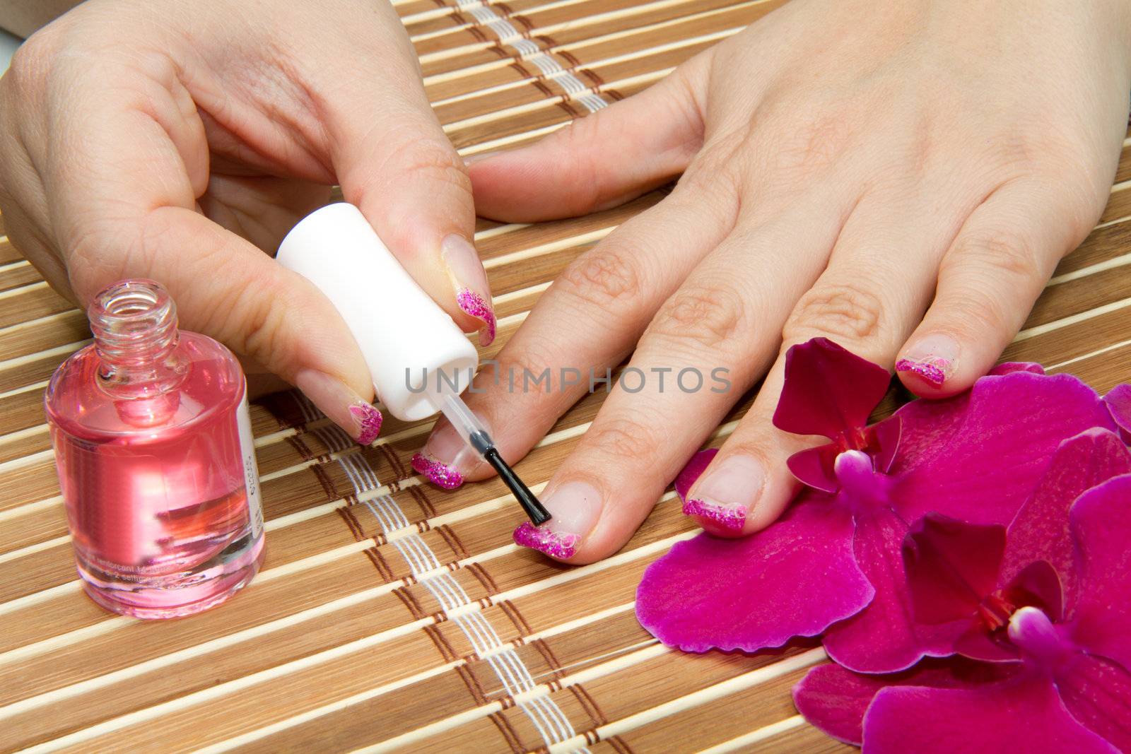 Beautiful hands with pink manicure holding purple orchid 