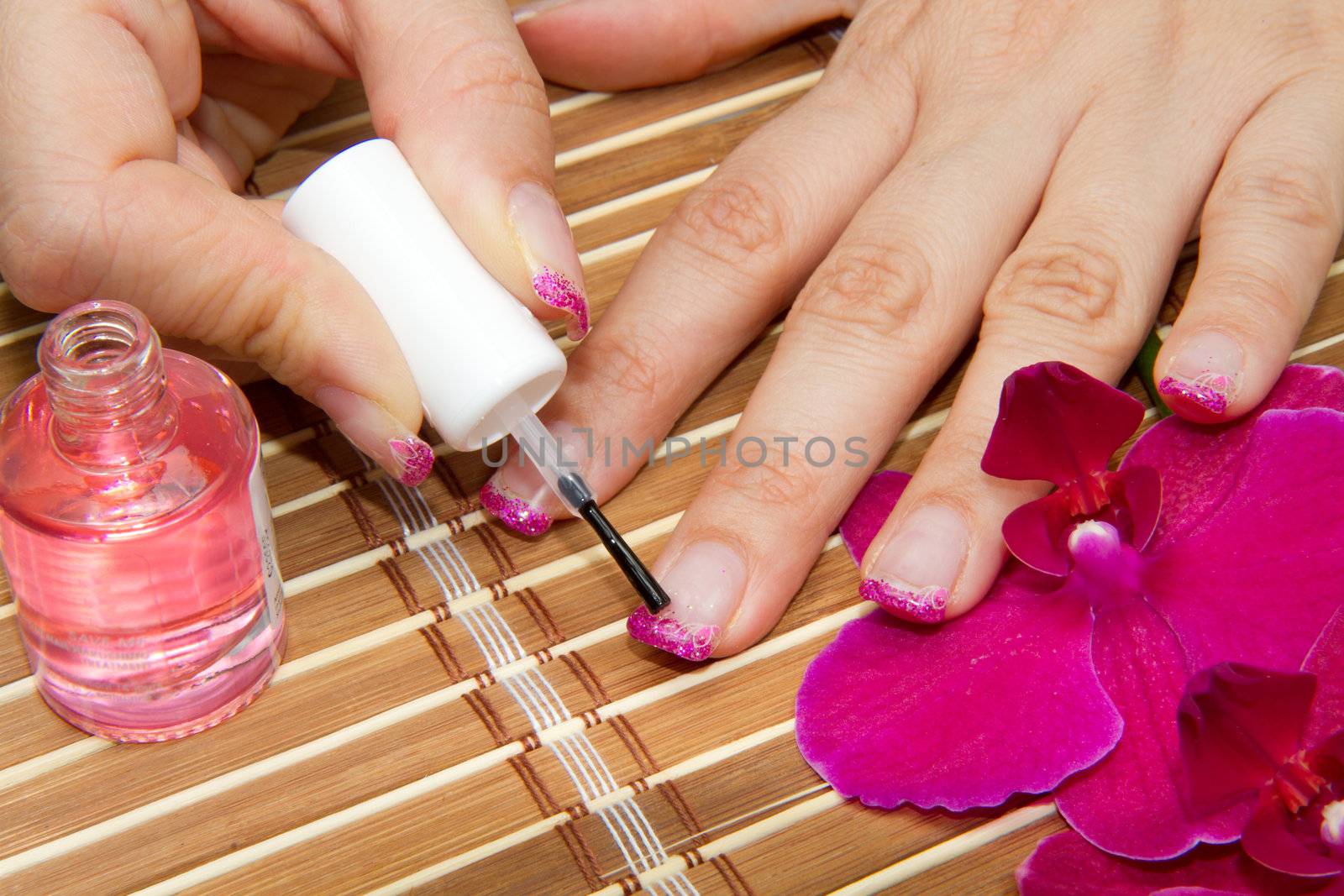 Beautiful hands with pink manicure holding purple orchid 