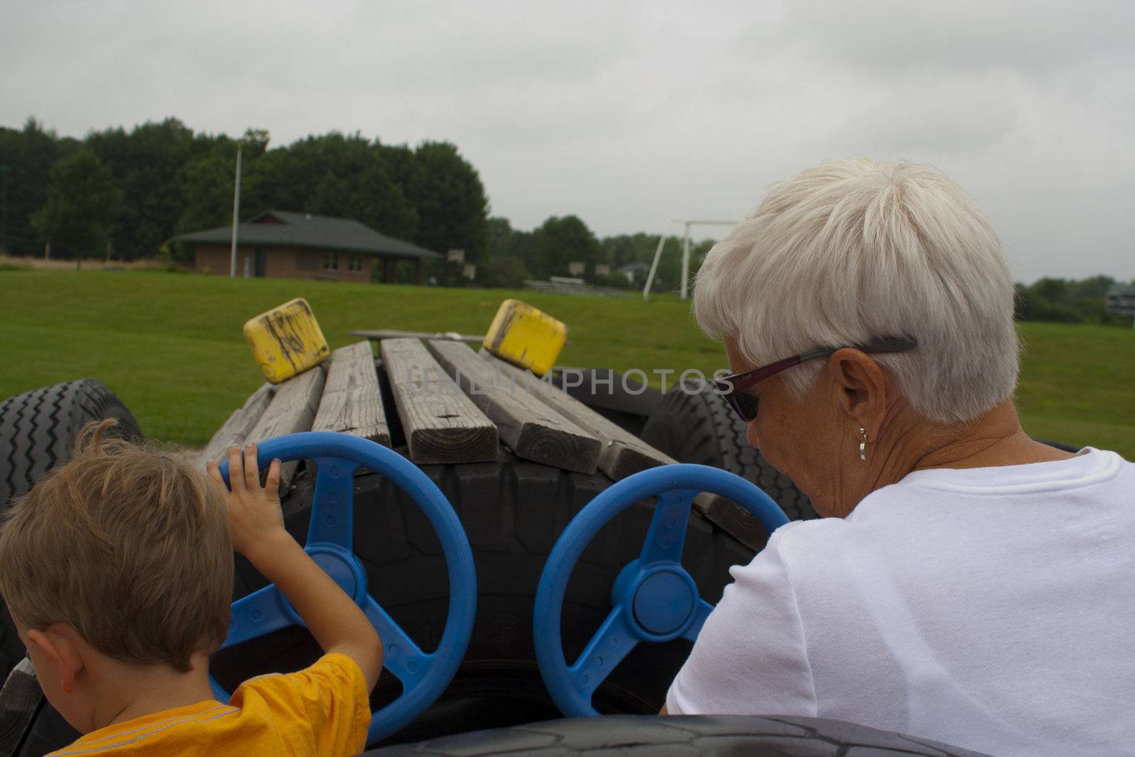 Grandmother and 3 year old grandson in playground car