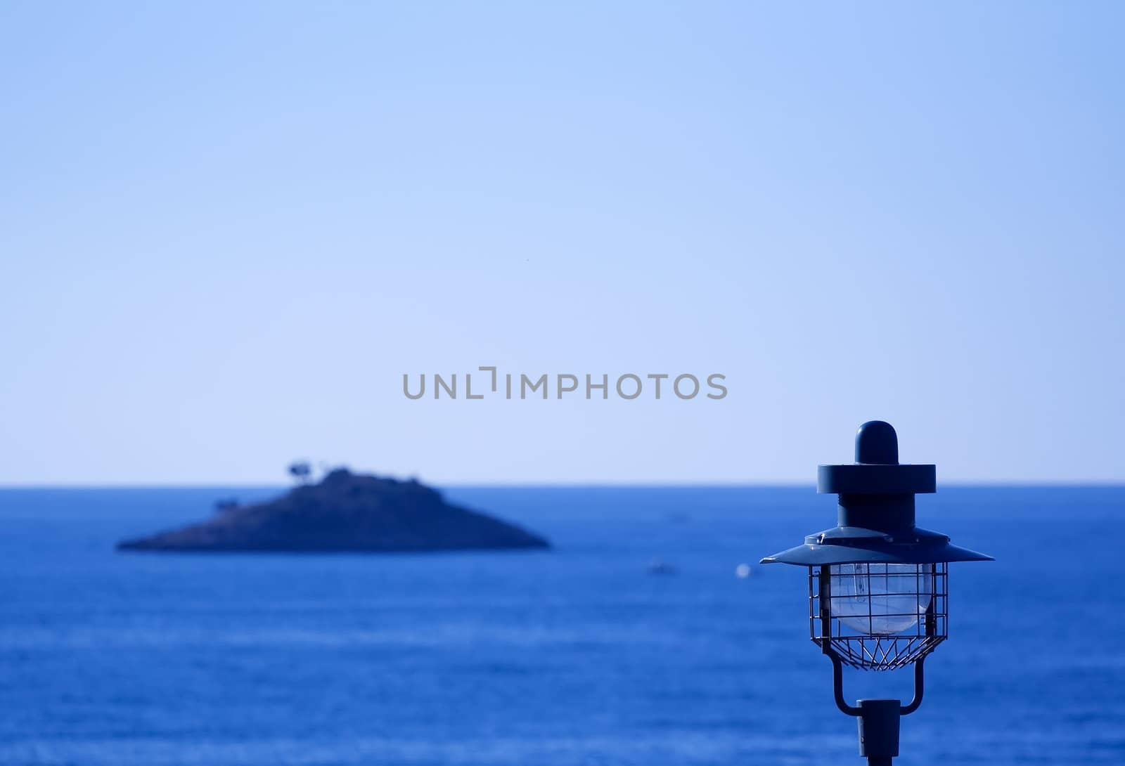 Street lamp in a small Mediterranean town wit a small island in background