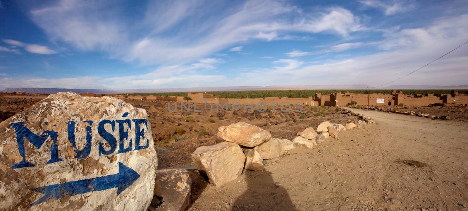 Blue arrow and museum painted on a stone in a small desert village in the south of Morocco