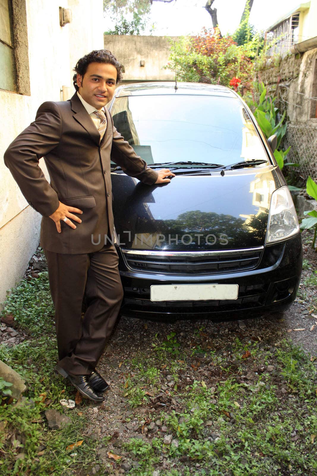 A young Indian man proud of his new car.