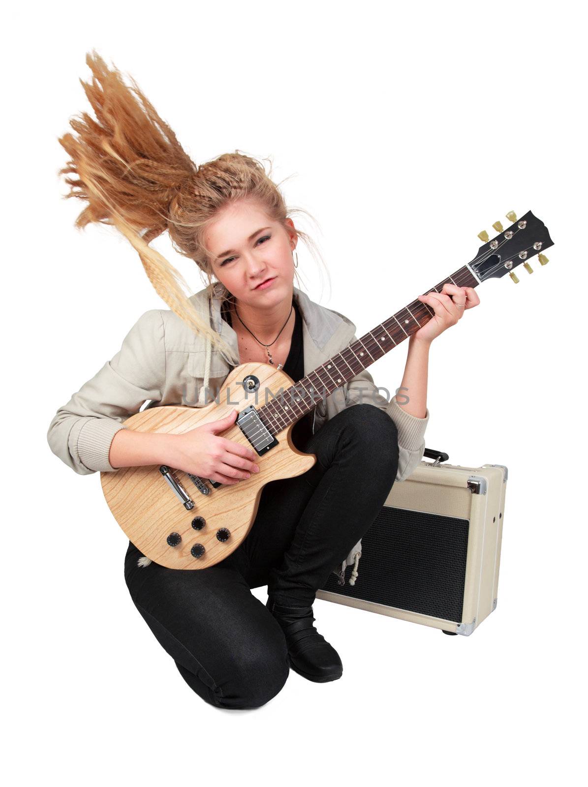 Blond rock teenage girl playing an electric guitar on her knees. Studio shot, isolated on white background.