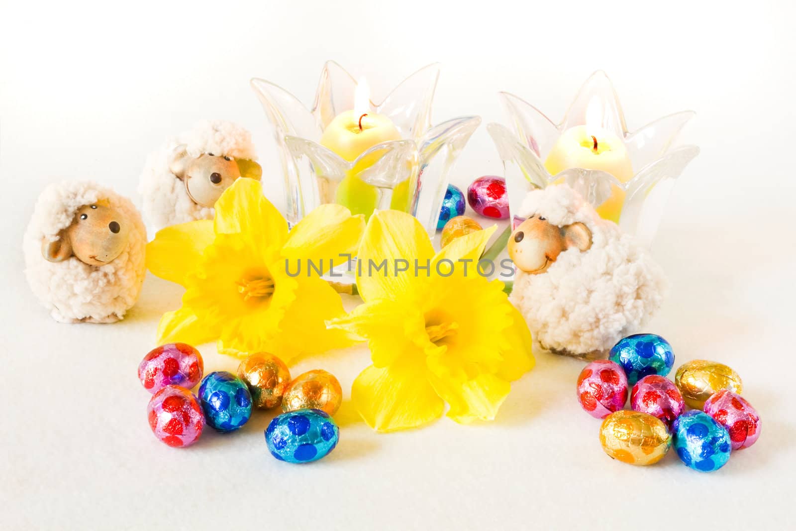 Easter decoration with chocolate eggs, sheep, daffodils and candles