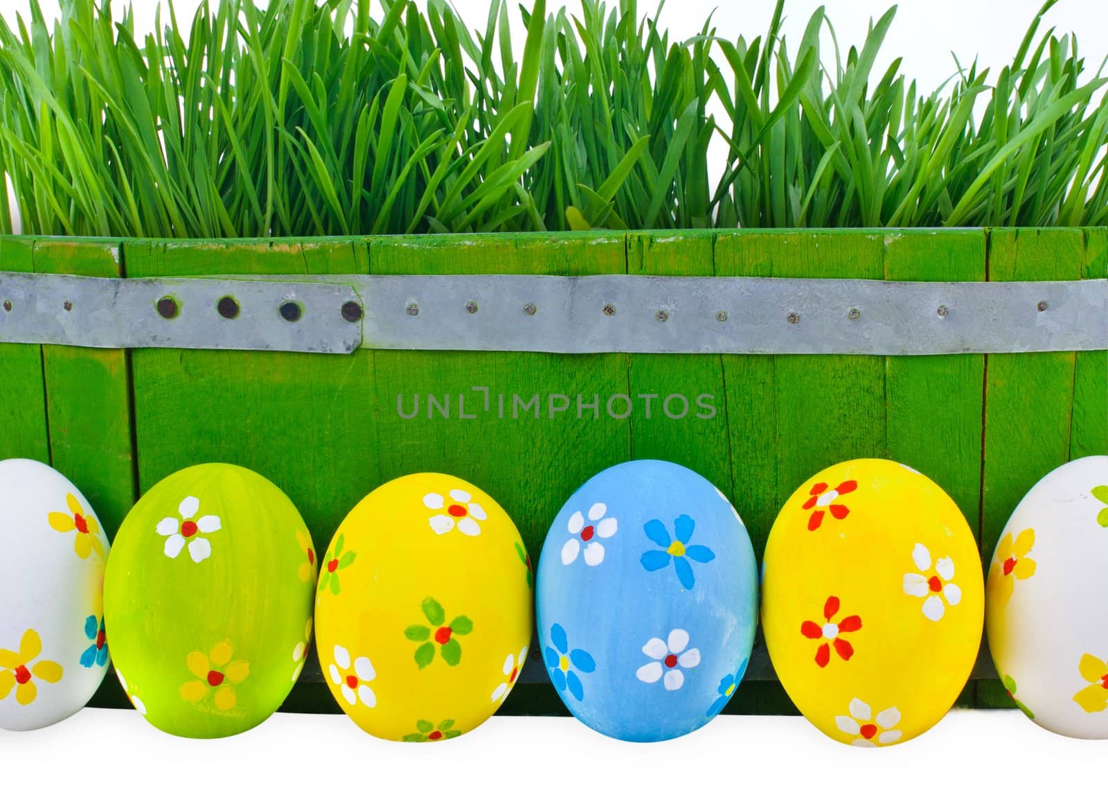 Easter eggs next to the bucket with the green spring grass