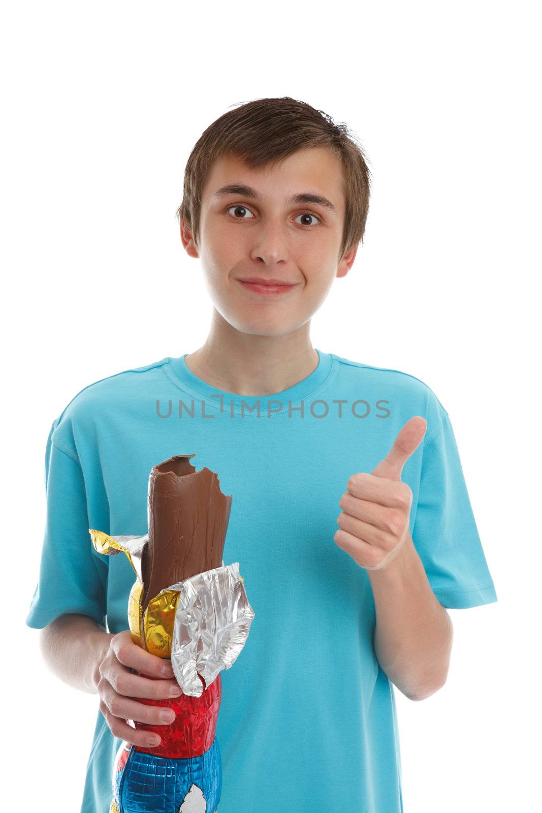 A boy wearing a blue shirt eating a delicious milk chocolate rabbit and showing a thumbs up sign of approval ir satusfaction.