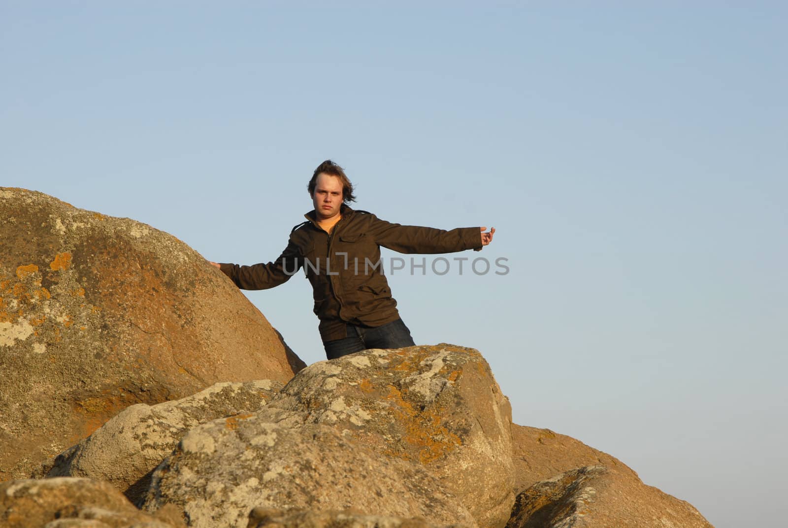 young man with arms wide open and the sky as background