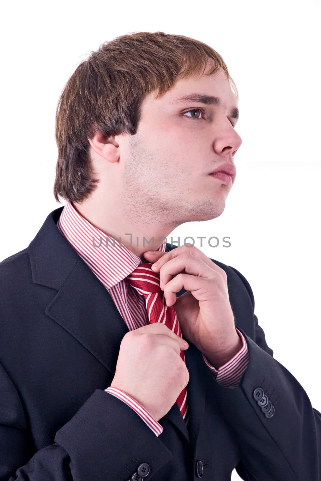 Young man wearing suit, adjusting tie. Isolated on white.