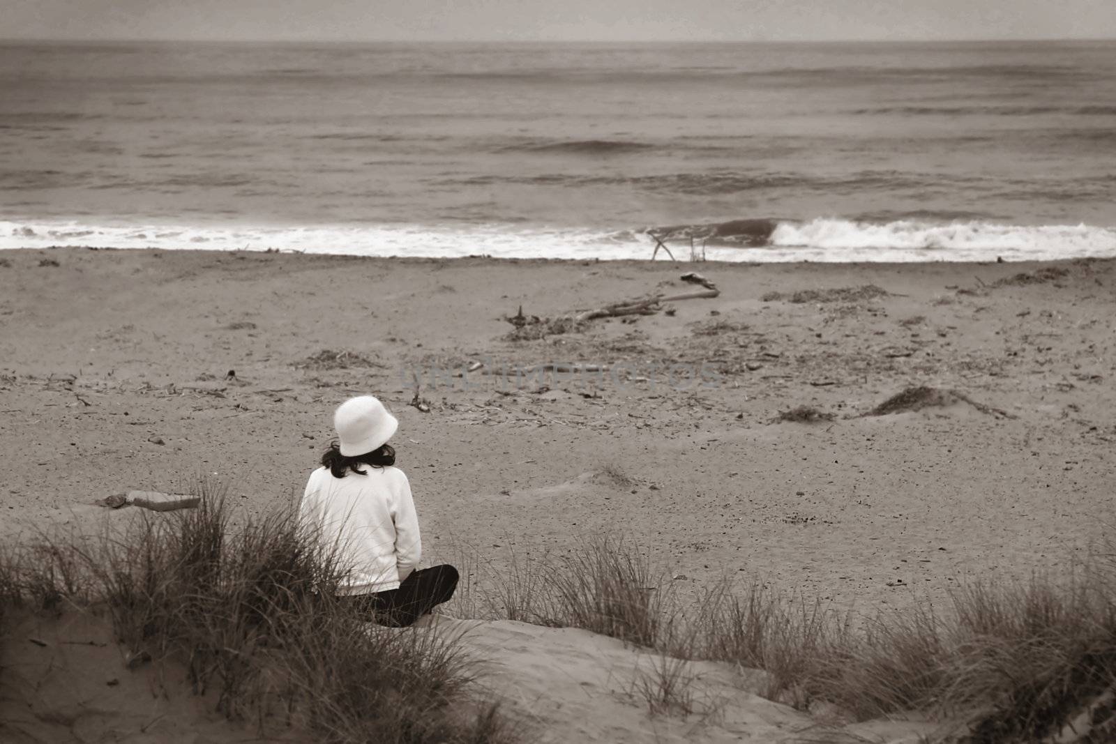 Young woman sitting at the beach looking over the ocean