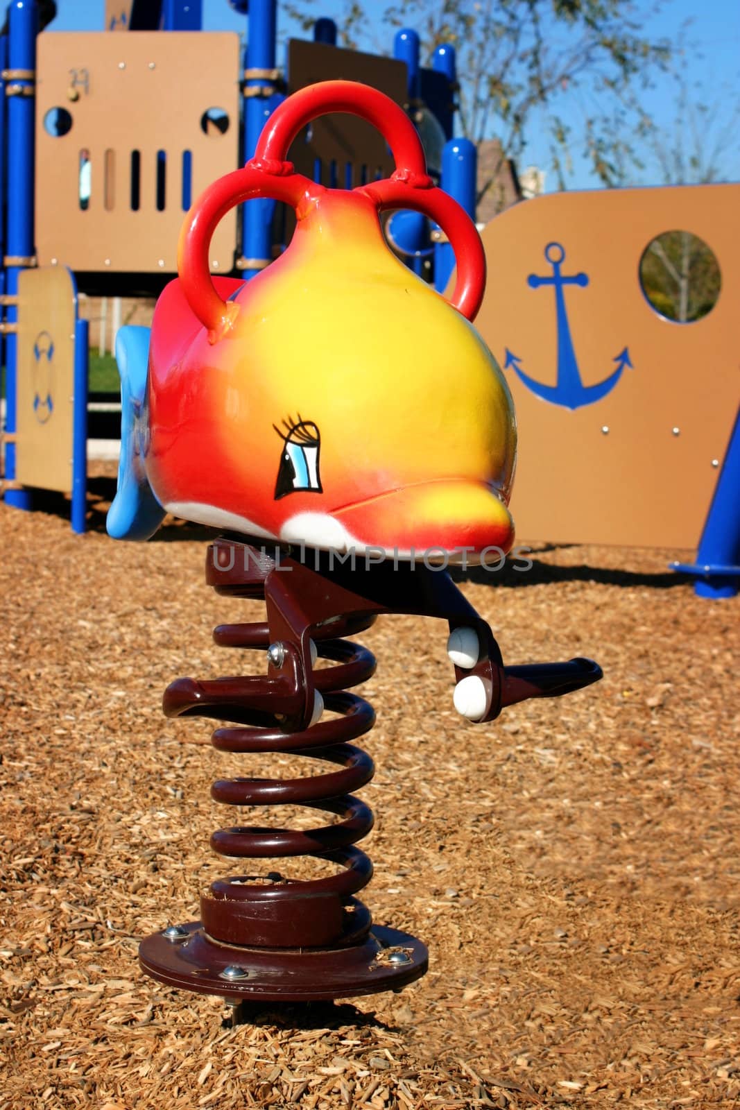 Colorful playground equipment with woodchips on the ground.