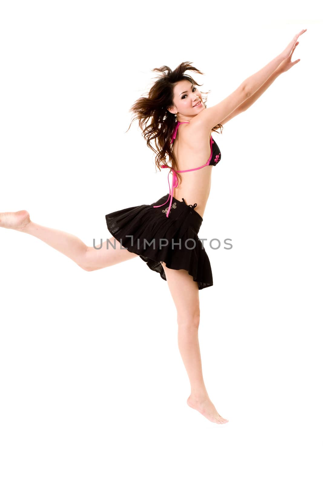 young woman in bkini top & skirt jumping freely and happily