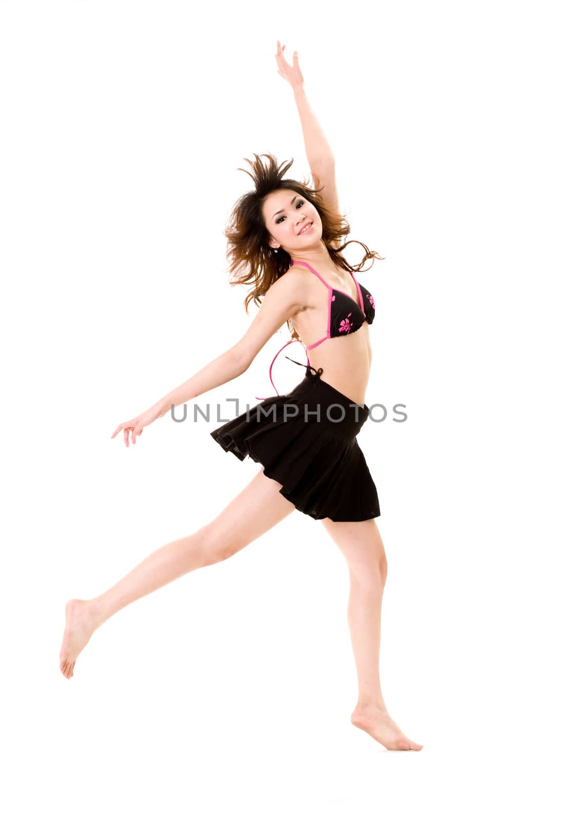 young woman in bkini top & skirt jumping freely and happily