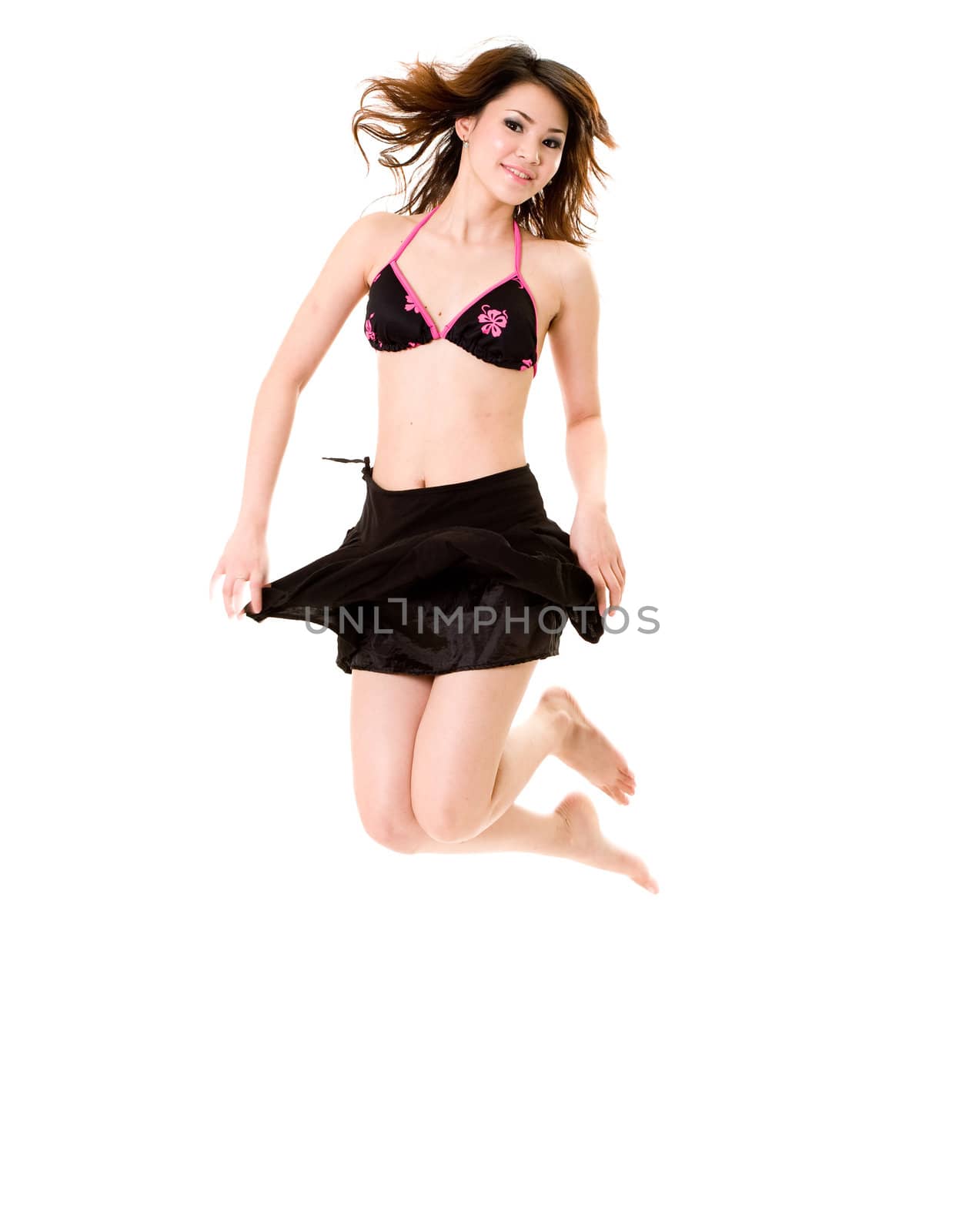 young woman in bkini top & skirt jumping freely and happily