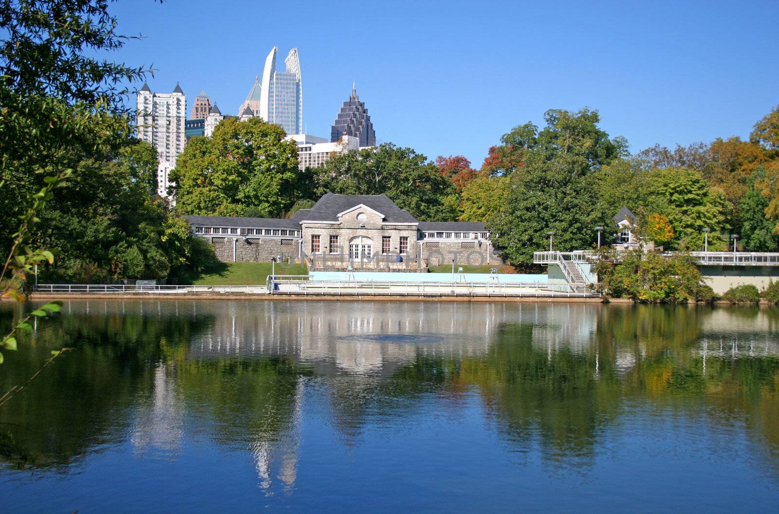 Poolhouse and city skyline across lake in park