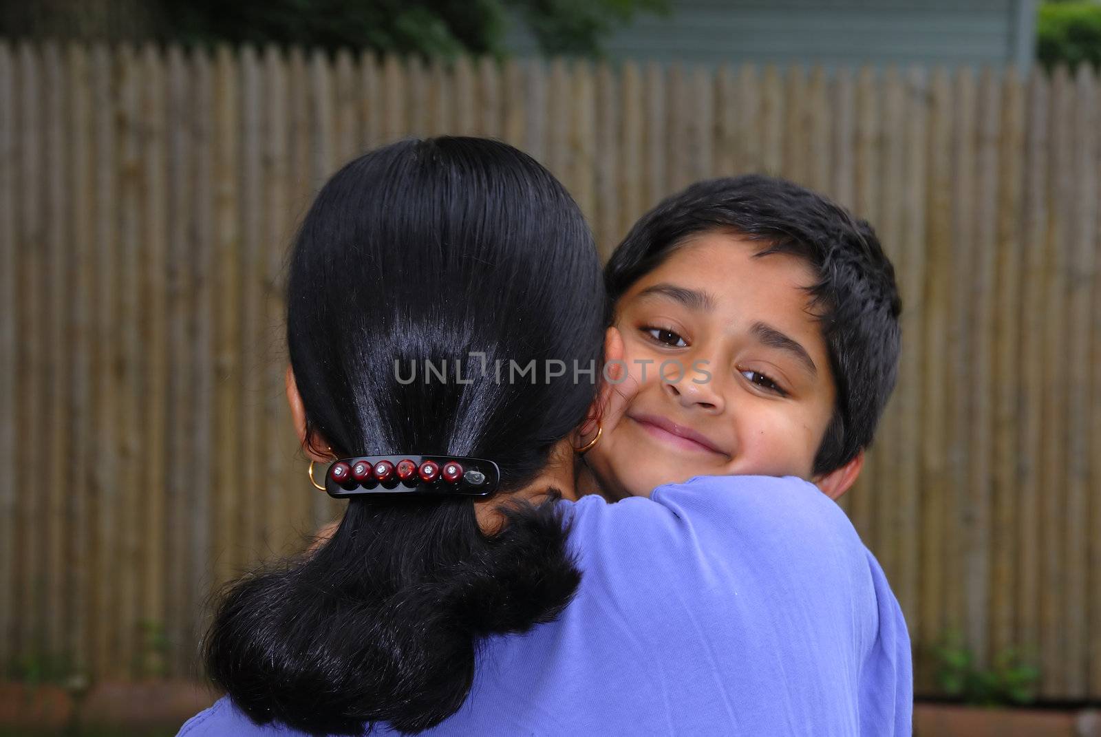 A happy Indian kid hugging his mother