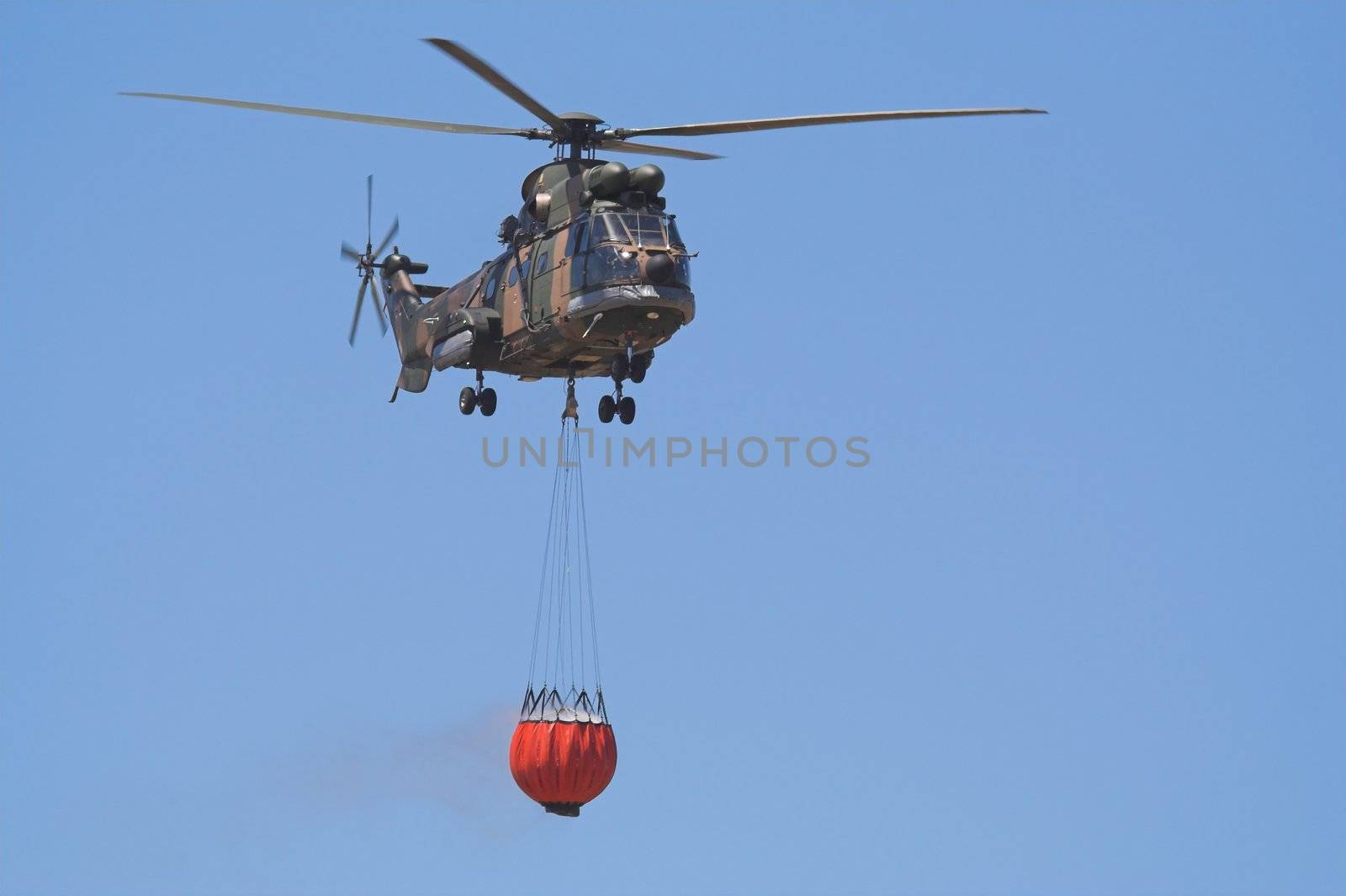 Air-Force Helicopter with a Bambi bucket filled to fight a forest fire