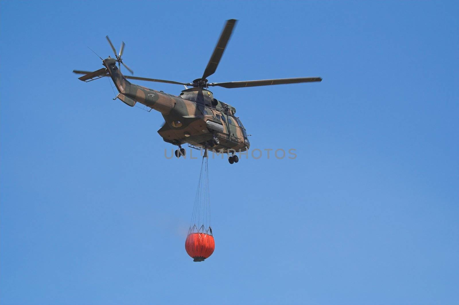 Air-Force Helicopter with a Bambi Bucket filled to fight a forest fire