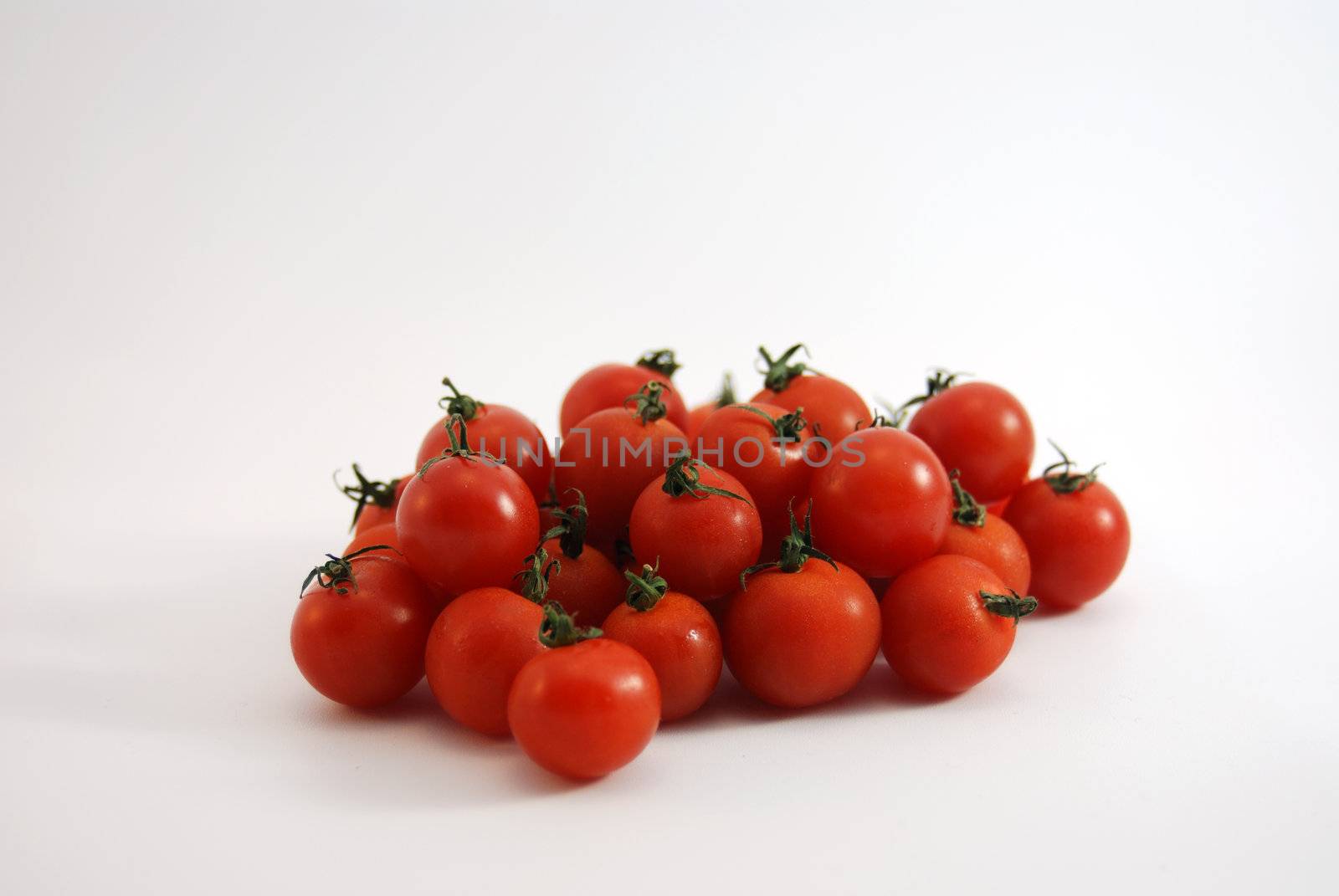 Fresh cherry tomatoes loose on white background.