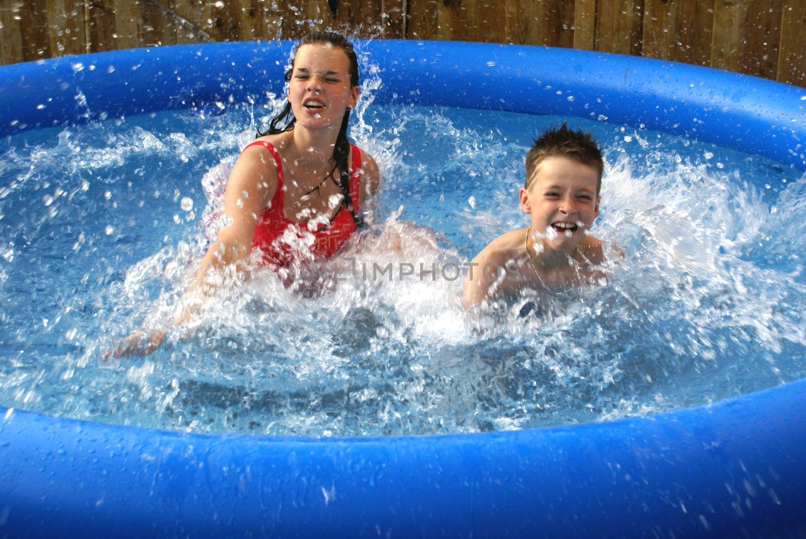 Two kids splashing in pool.                