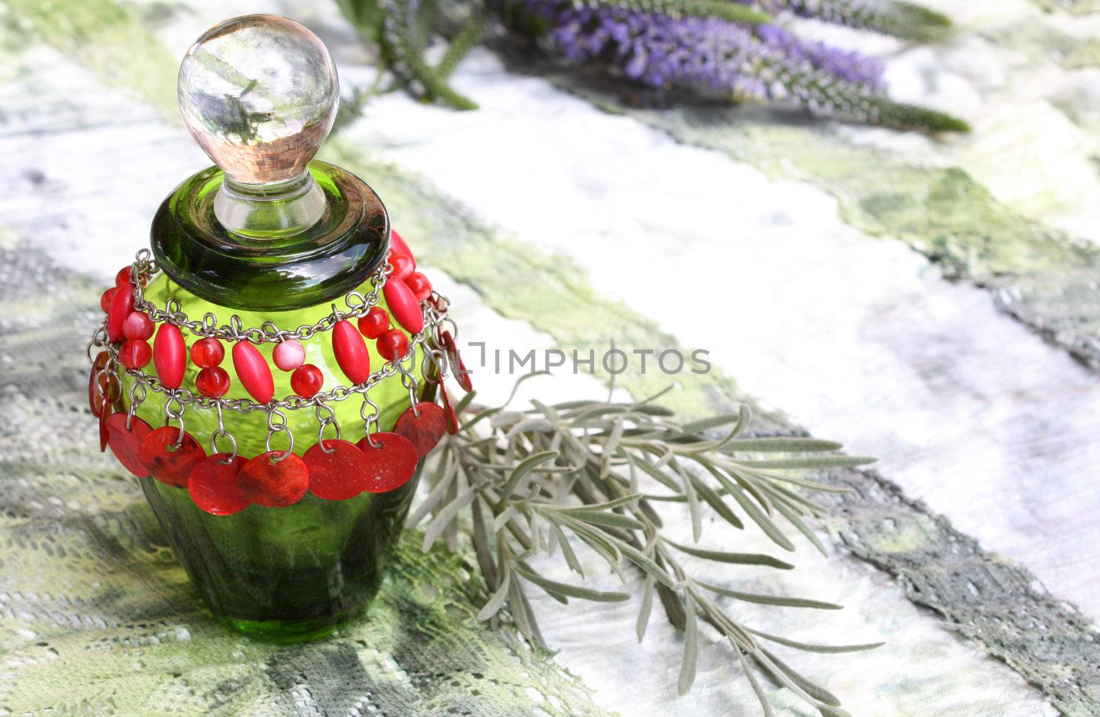 Stained green perfume bottle with read bead bracelet and lavender