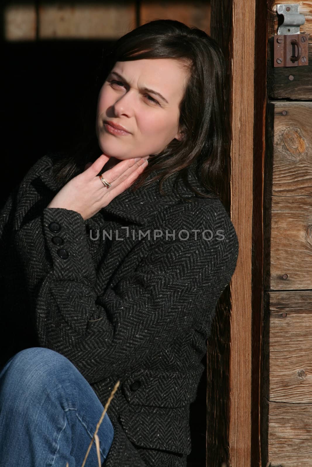 Beautiful brunette female leaning against wooden barn