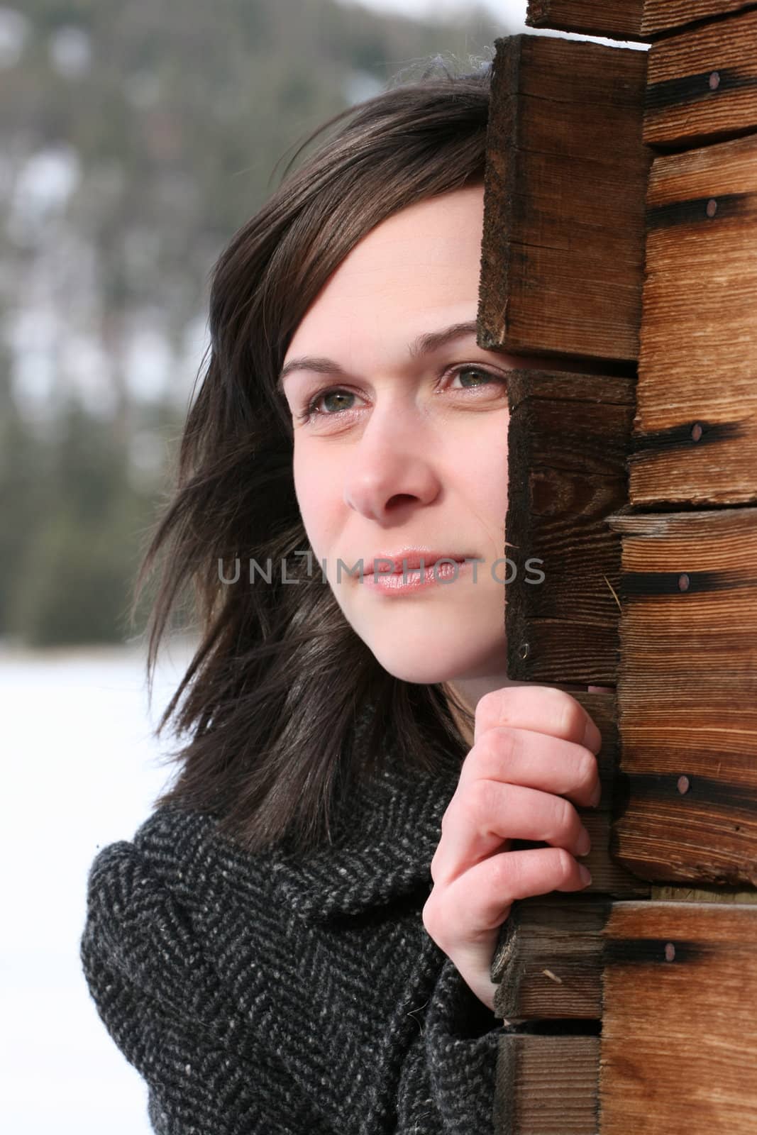 Beautiful brunette female leaning against wooden barn