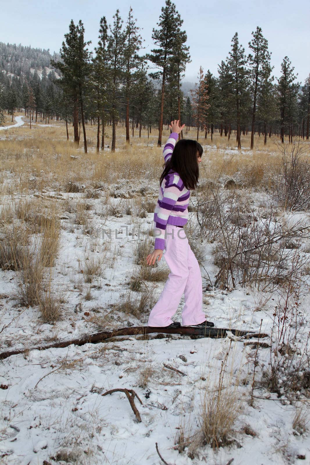 Young brunette teen playing in the field after the snowfall