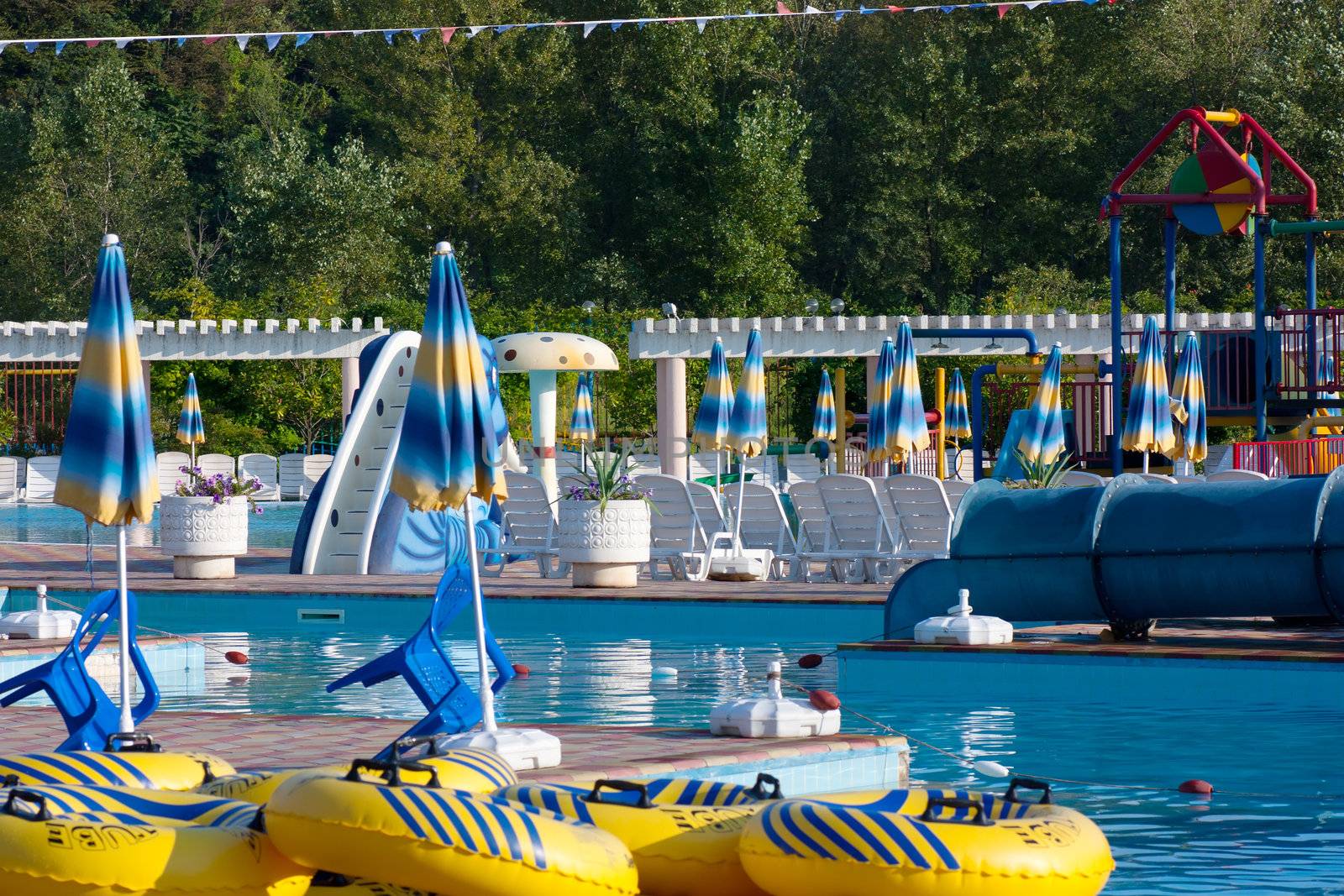 Swimming pool, inflatable rings, sunshades and plastic chairs in waterpark after closing