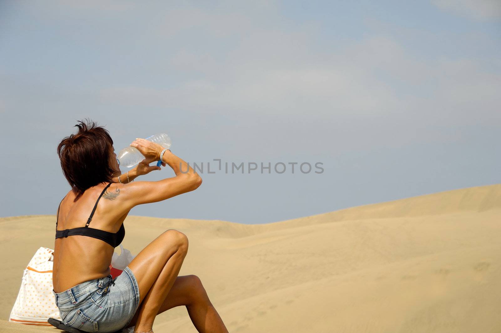 Woman is drinking water in the desert