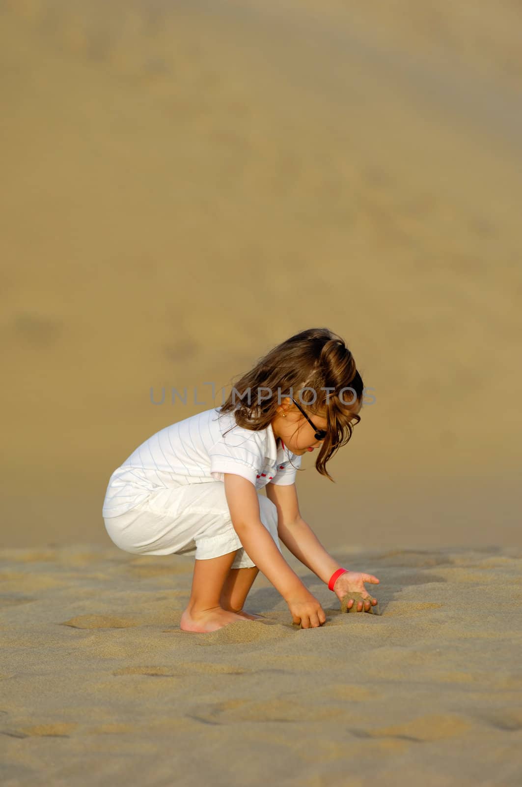 Child is playing with sand in the desert