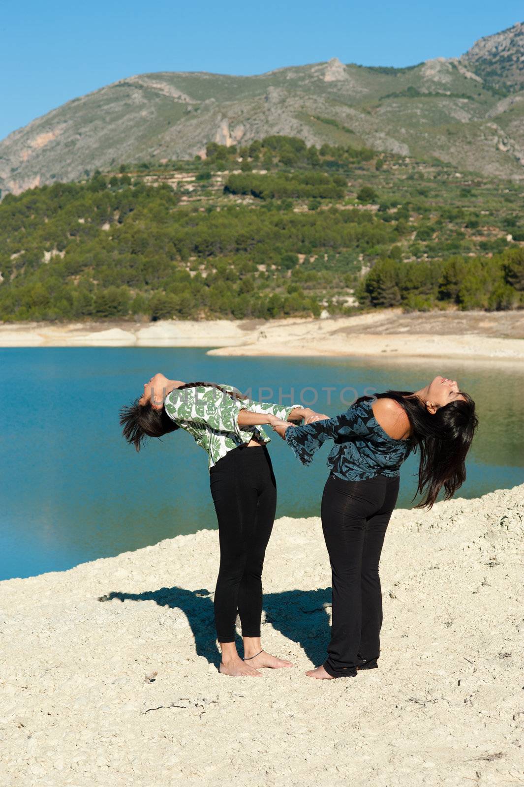 Mother and daughter, early morning yoga lakeside