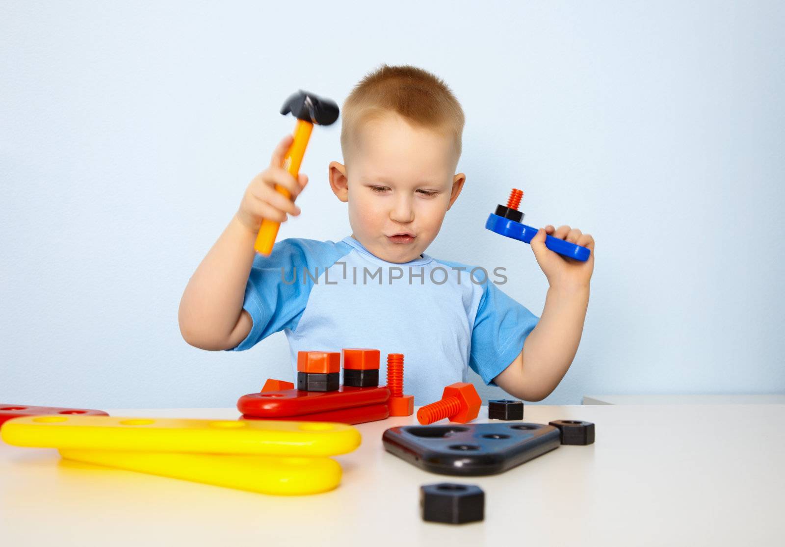 Little boy playing with a toy tool on blue background