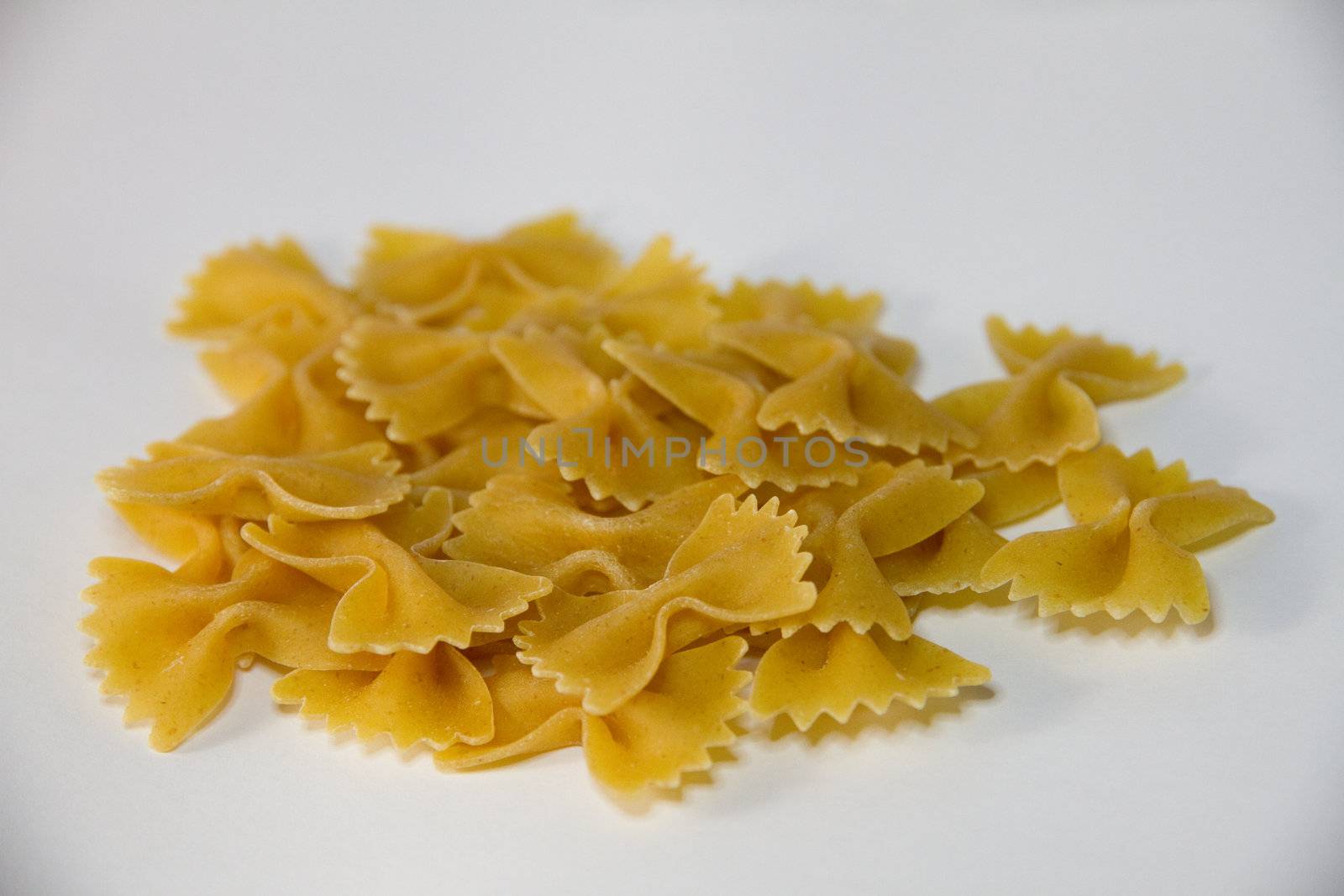 A close-up view of many whole grain Farfalle bowtie pasta uncooked with white backgound