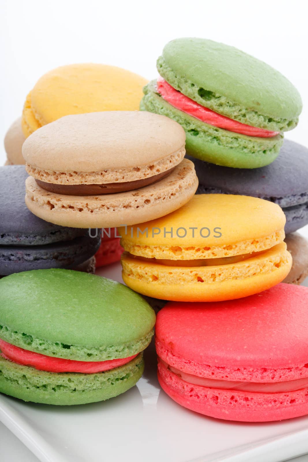 Delicious assorted macaroons on a serving dish.  White background.