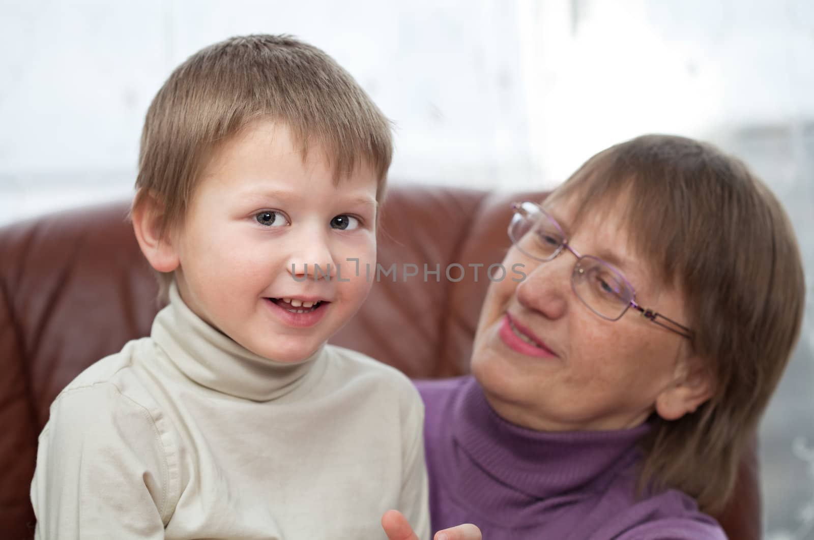 Little boy with his grandmother sitting in a leather armchair at home