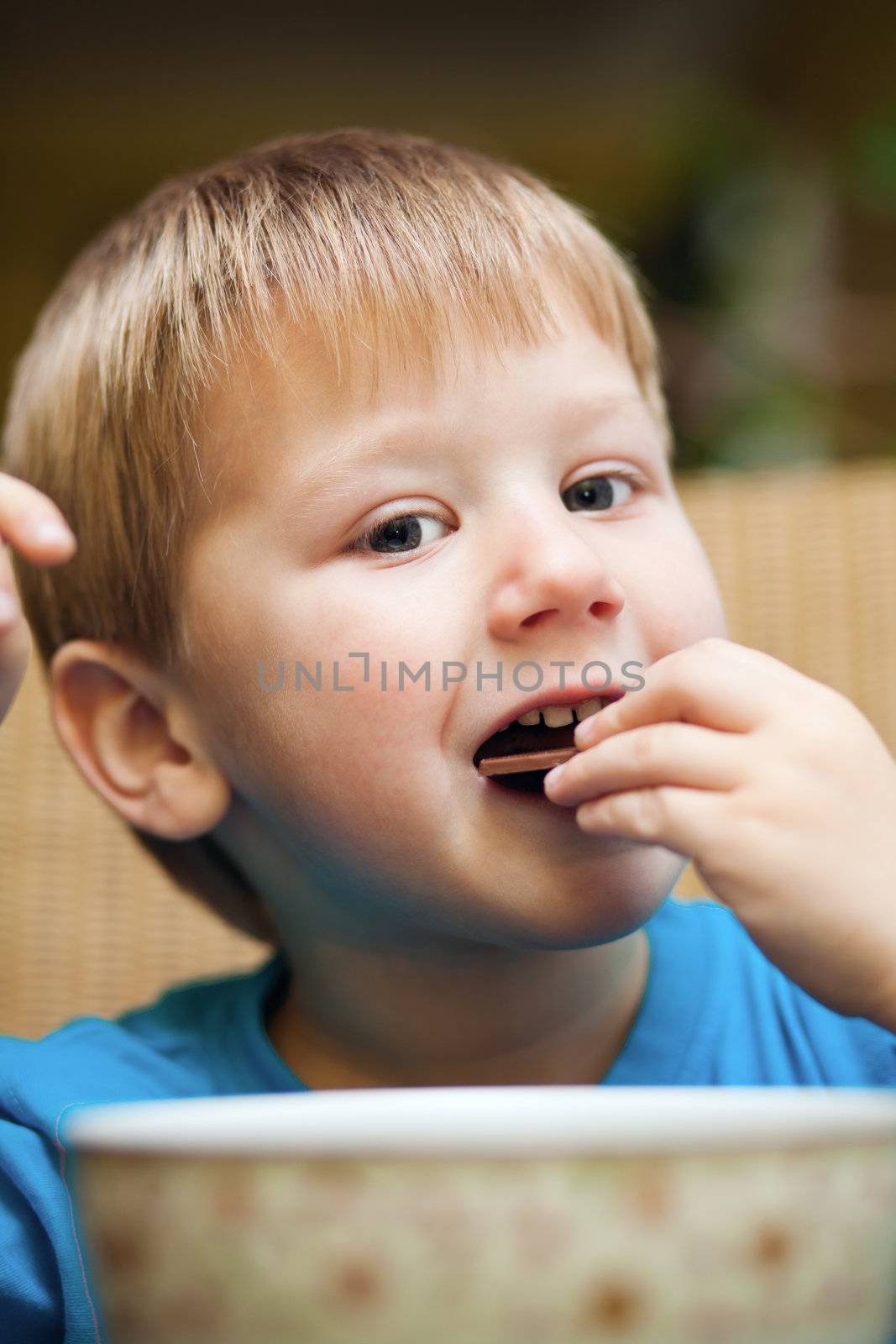 Cute little blond boy eating a snack 
