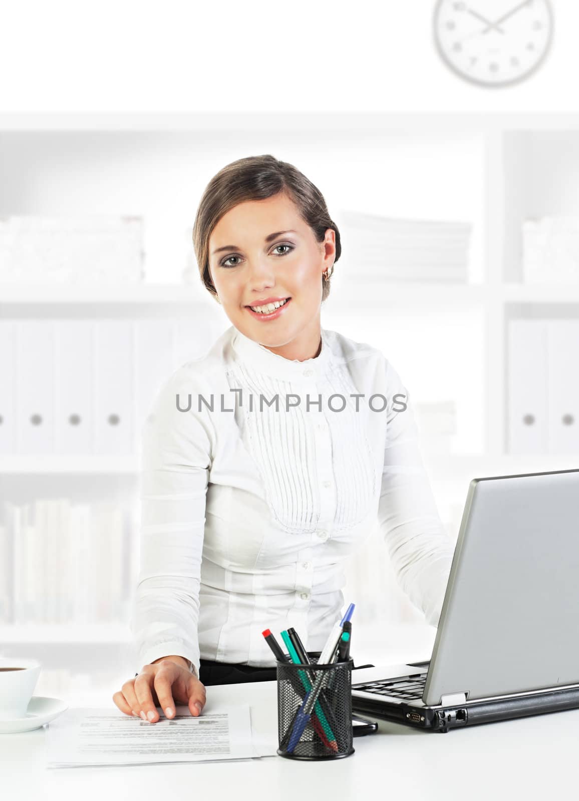 Young pretty businesswoman sitting at her workplace