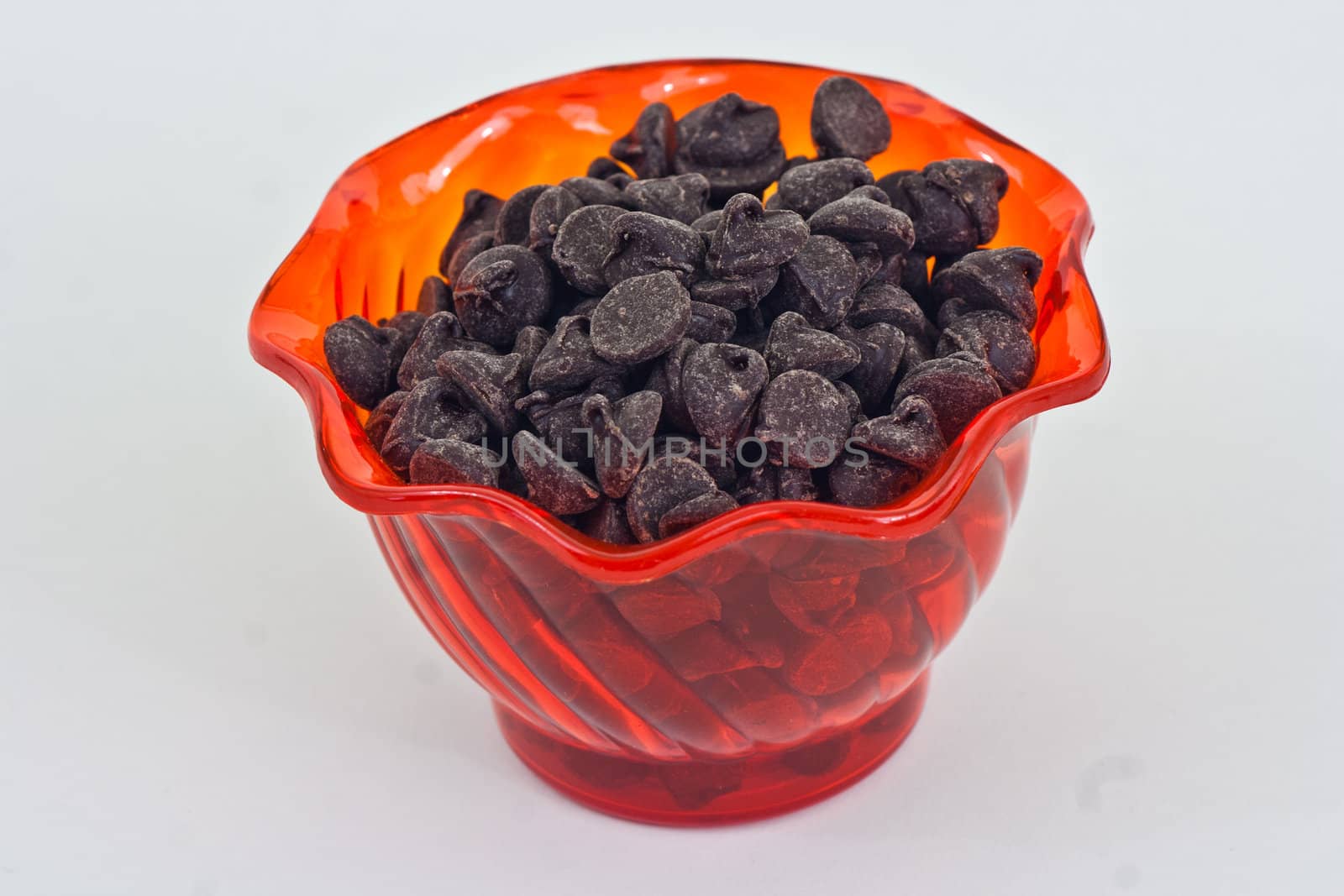 An orange cup with chocolate chips on a white background.