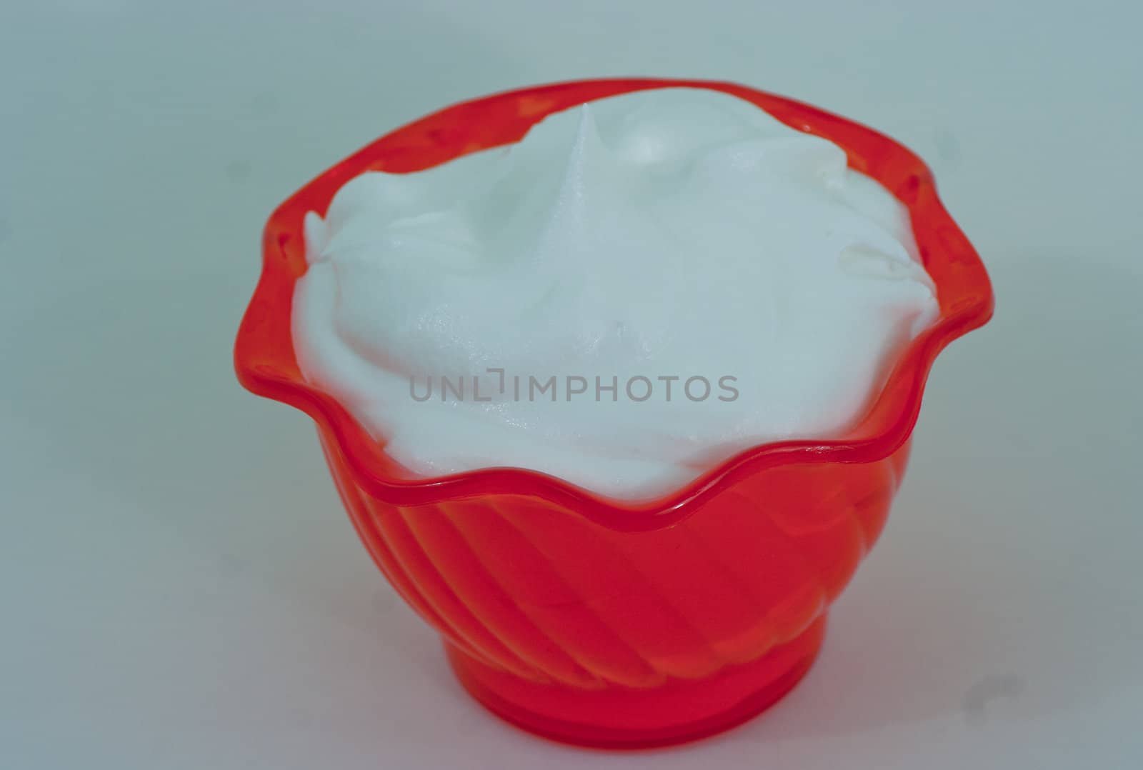 White whipped toping in an orange cup with a white background