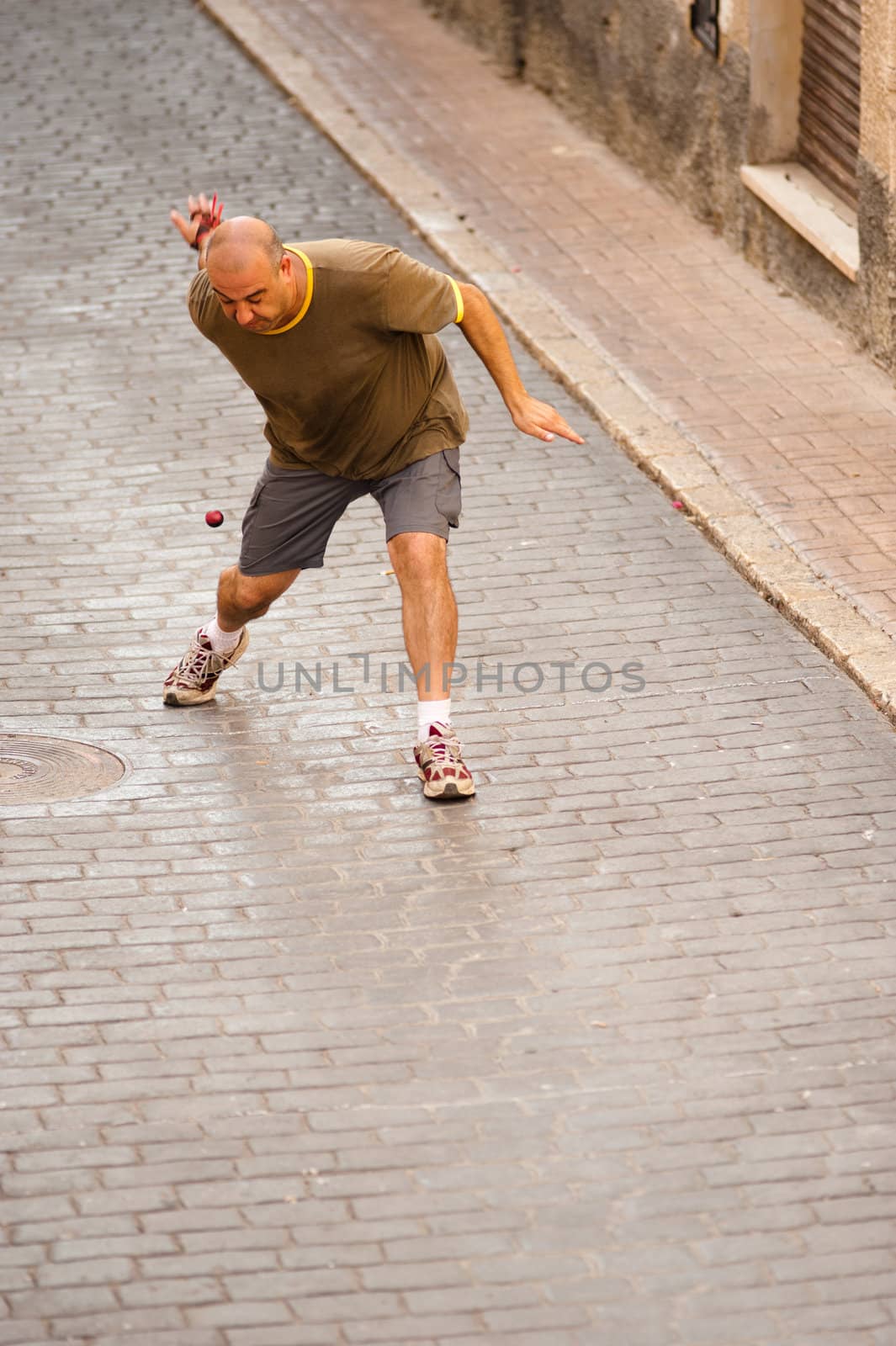 Traditional Spanish sportsman performing a powerful serve at a pelota match