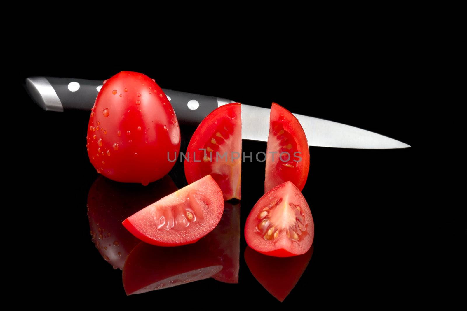 Fresh tomatoes and knife on black background by lavsen