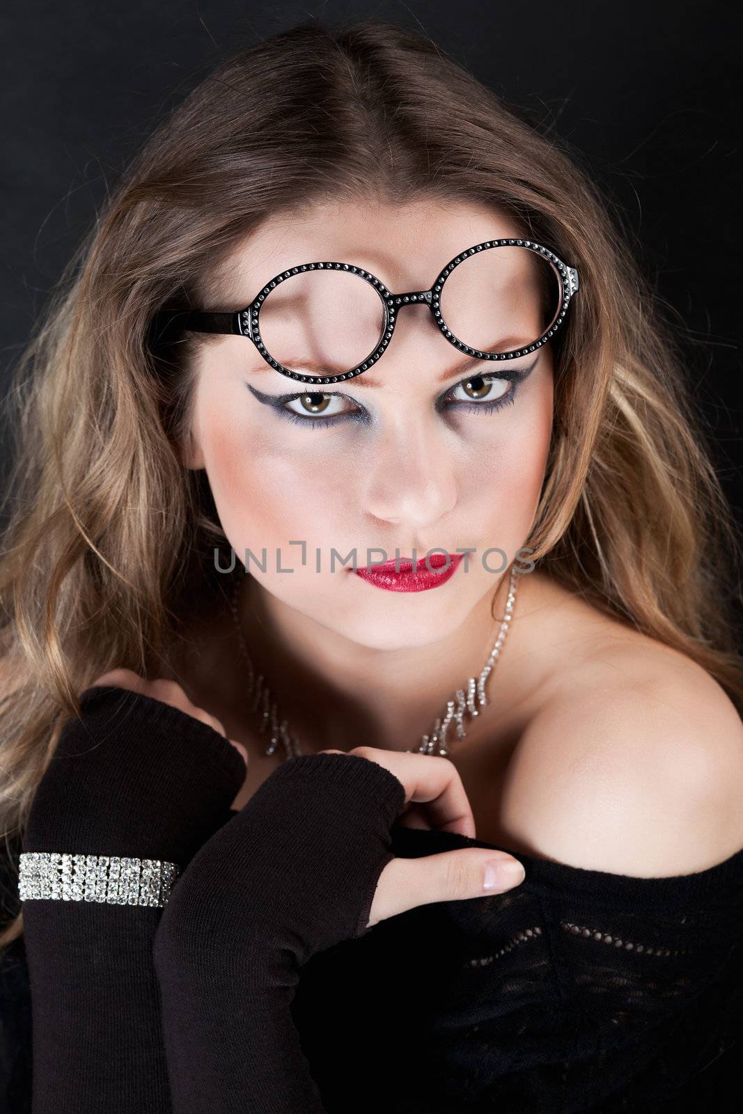 portrait of a young girl with glasses on her forehead, looking at the camera