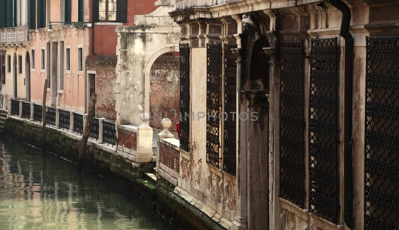 Image of the walls of houses near the water on a small canal in Venice.