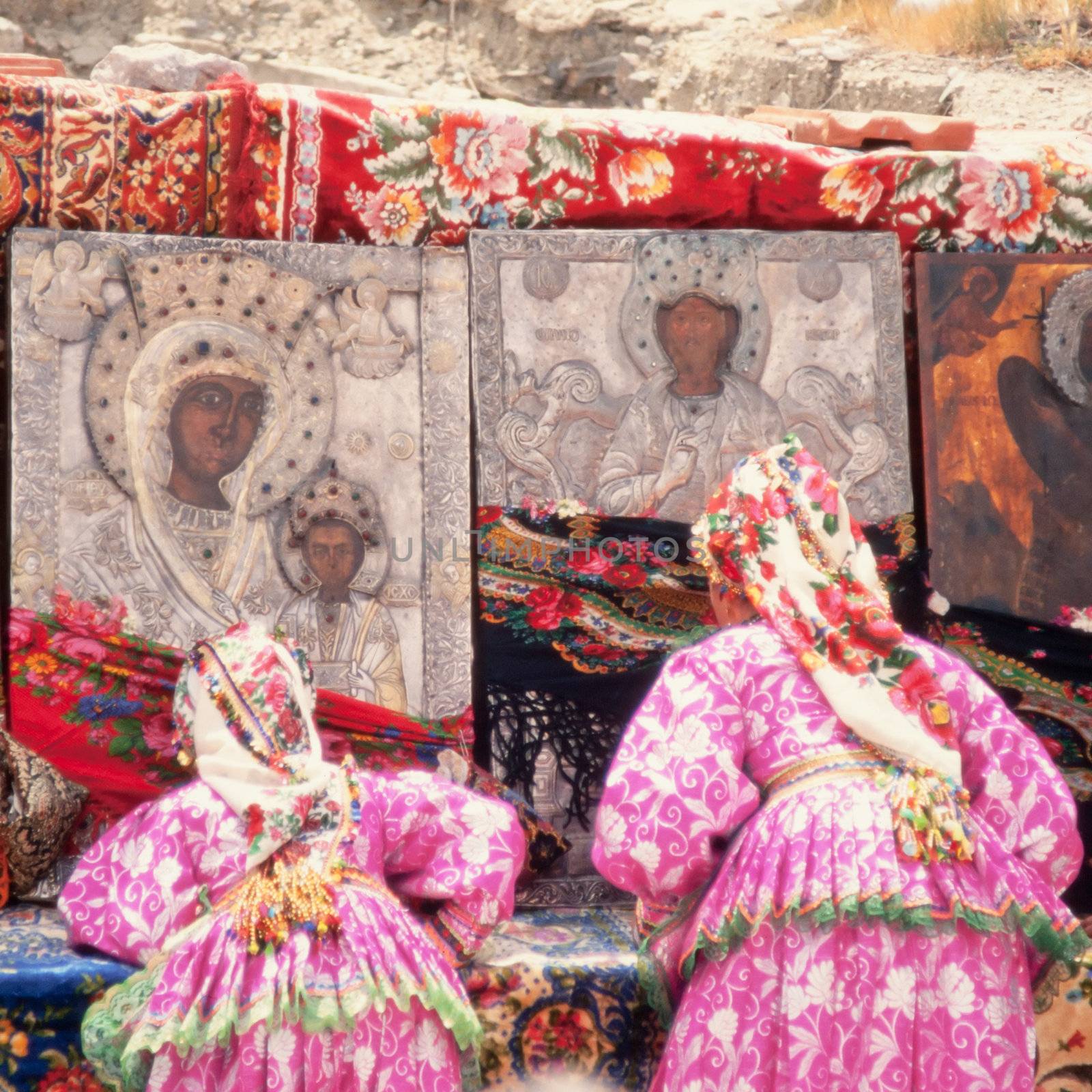 Orthodox Greek Easter Holiday: women in traditional dresses pray in front of icons outside the church.