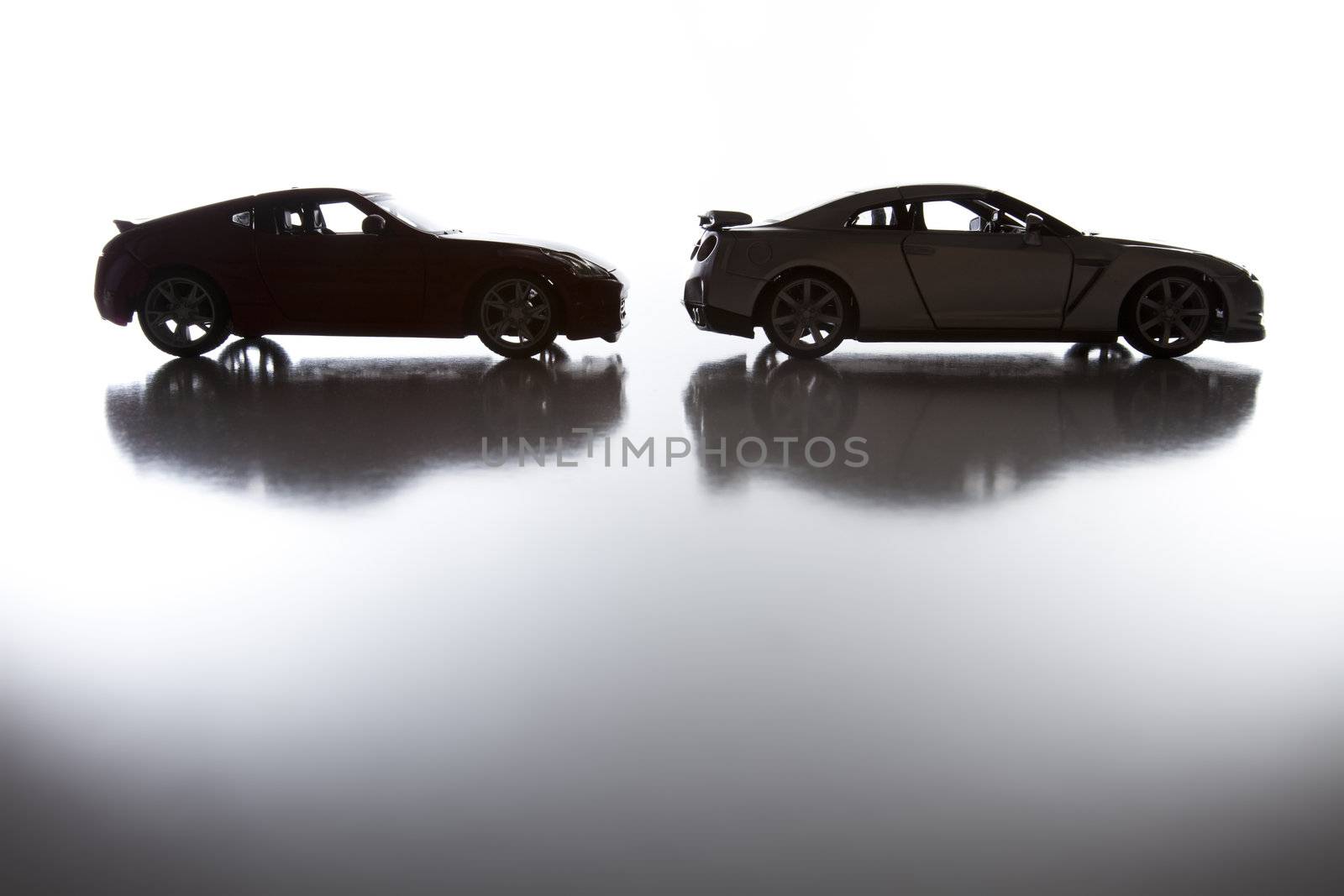 Silhouette of Sports Cars on Reflective Surface Against a White Background.