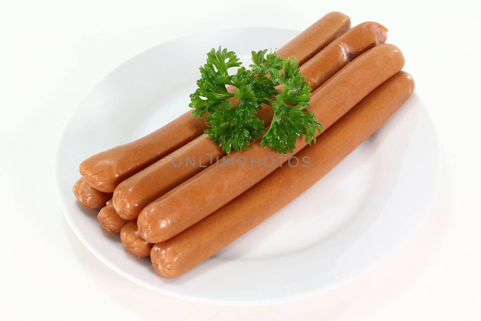 Vienna sausages and parsley on a white plate