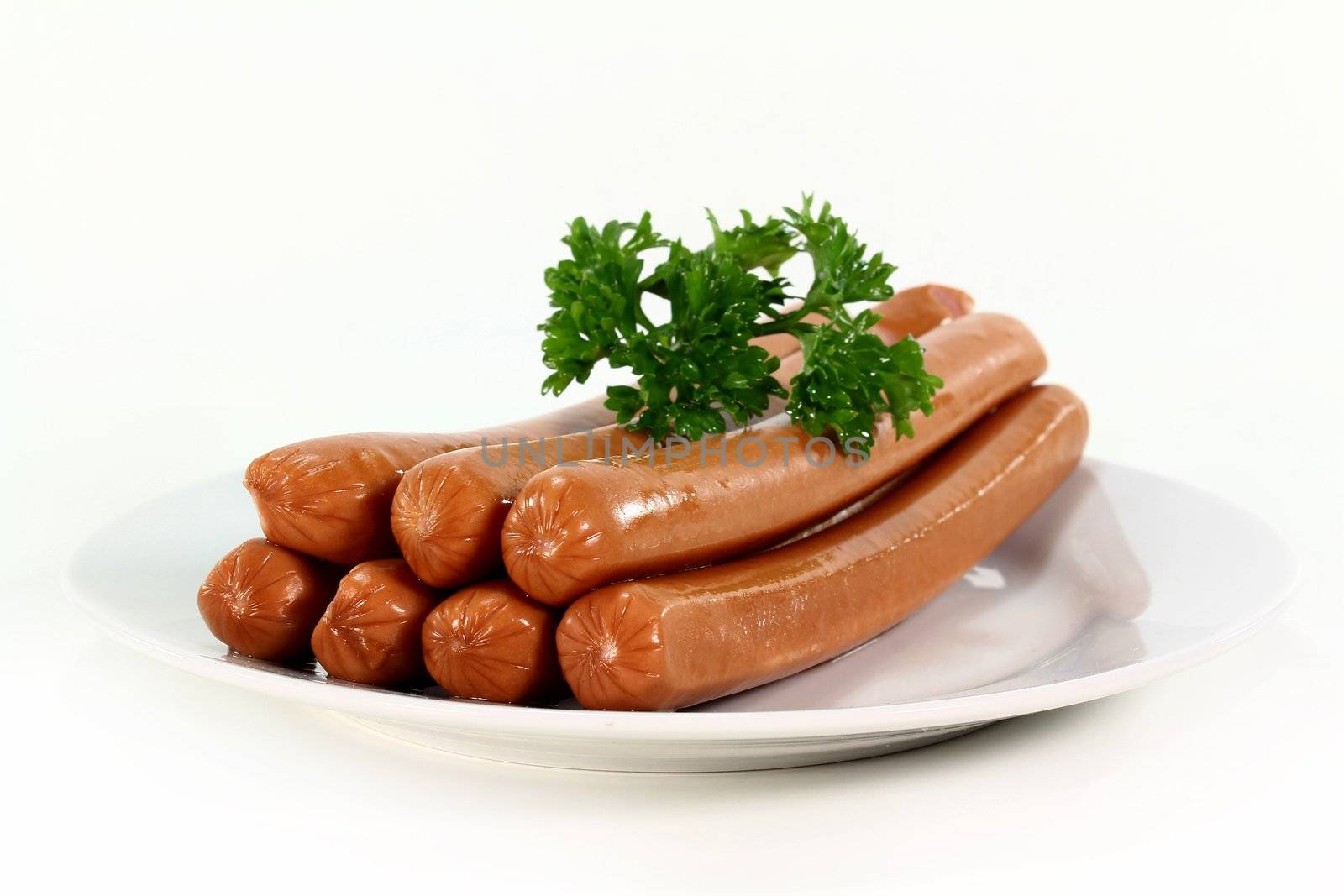 Vienna sausages and parsley on a white plate